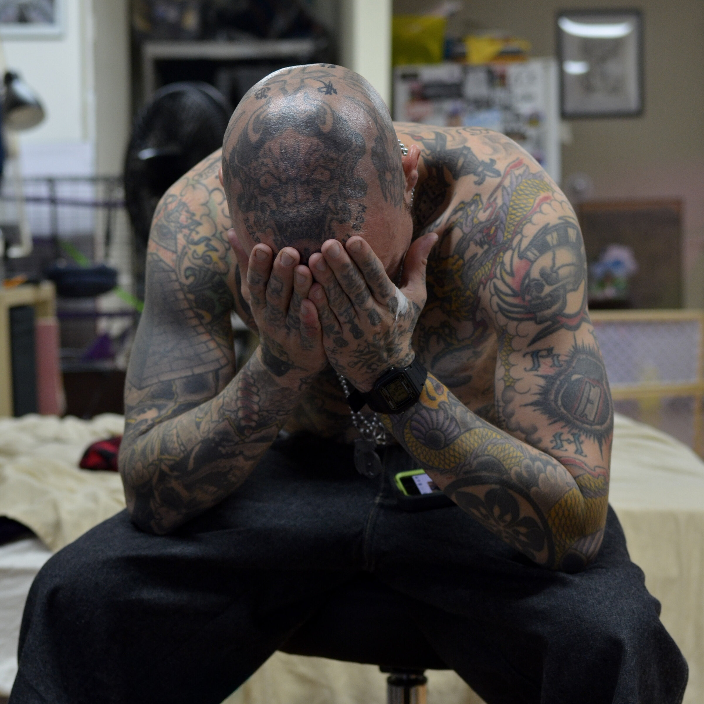 Heavily tattooed man, head in hands