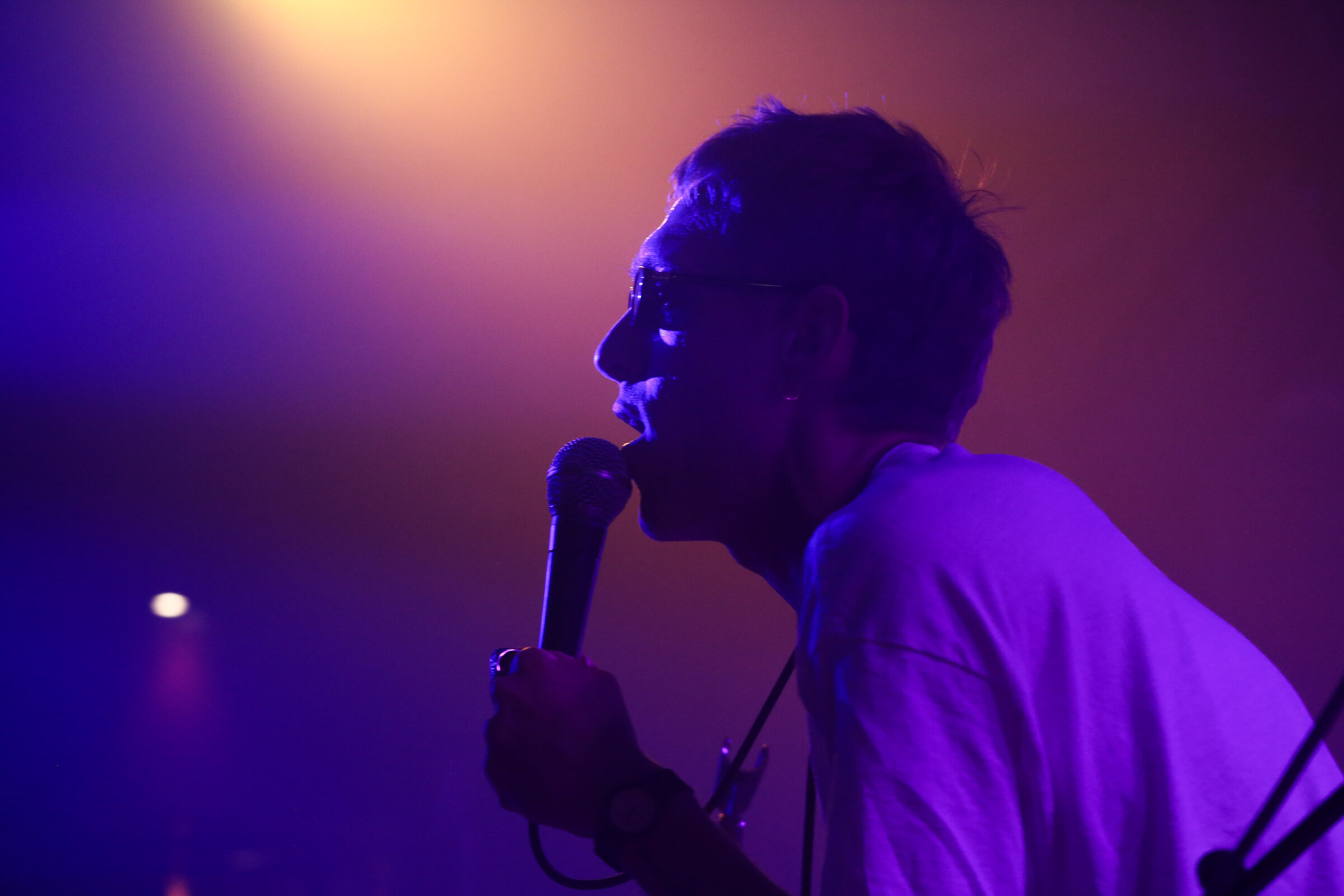 Singer under purple stage light, mid-phrase
